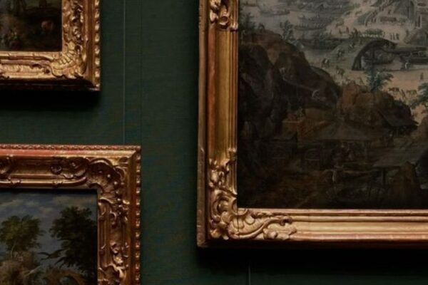Multiple ornate gilt-framed paintings hung on a deep green wall, depicting landscape and pastoral scenes.
